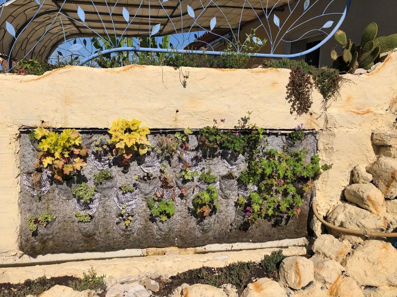 Conception d’une cascade et mur végétalisé sur un mur en fausses pierres. Mur vegetal